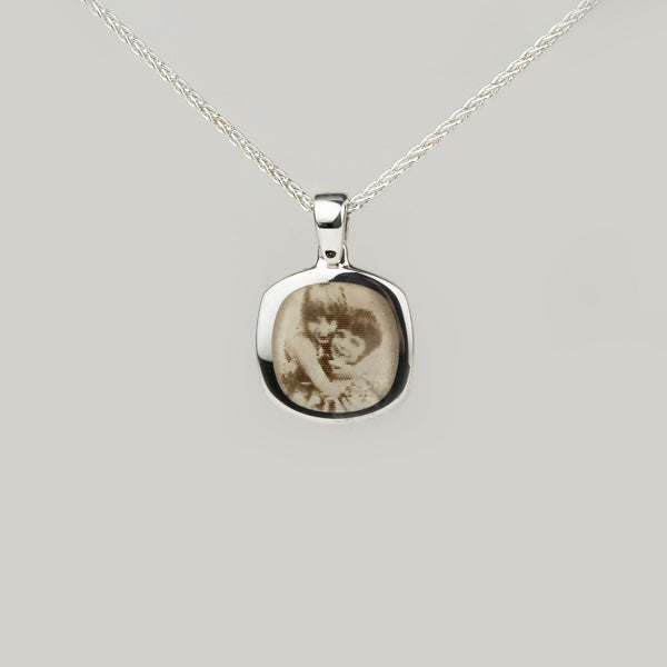 A sterling silver signet pendant with a photo engraving of two children.